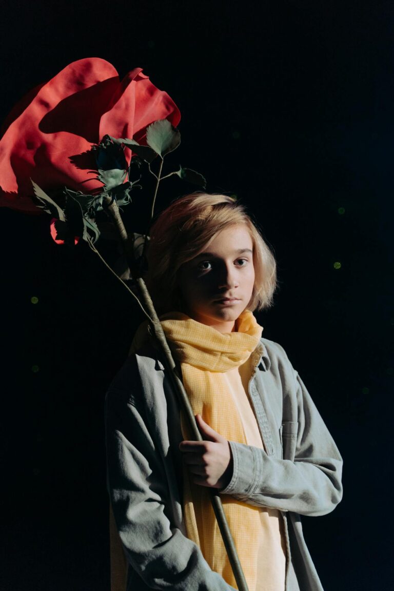 A young person in cosplay with a giant red rose, inspired by a literary character.